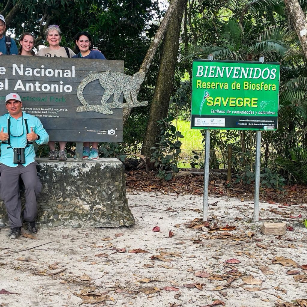 Tour group at the Manuel Antonio National Park entrance sign with Wakoo Tours guide