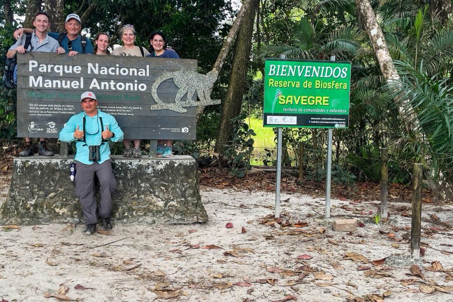 Tour group at the Manuel Antonio National Park entrance sign with Wakoo Tours guide