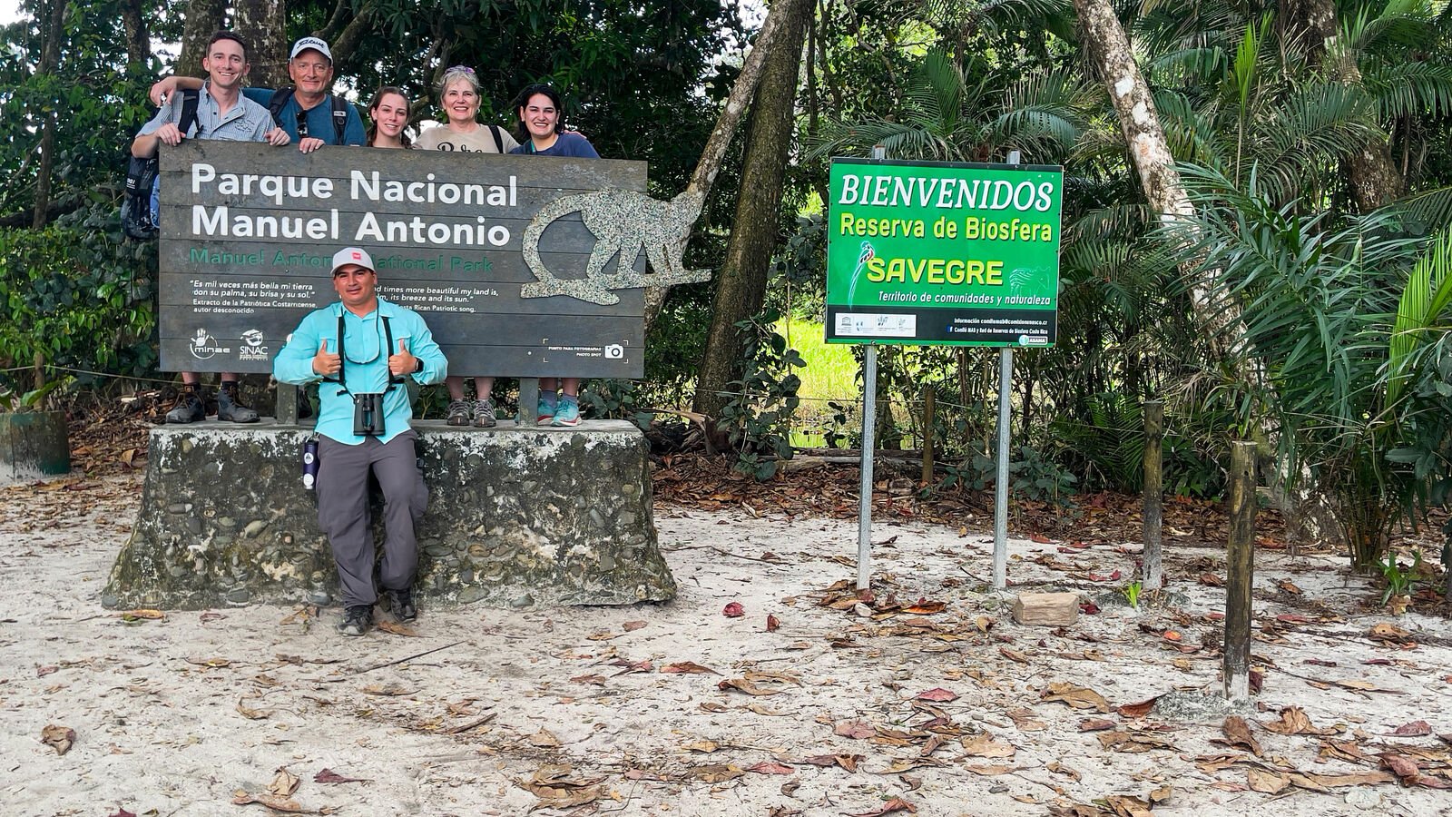 Tour group at the Manuel Antonio National Park entrance sign with Wakoo Tours guide