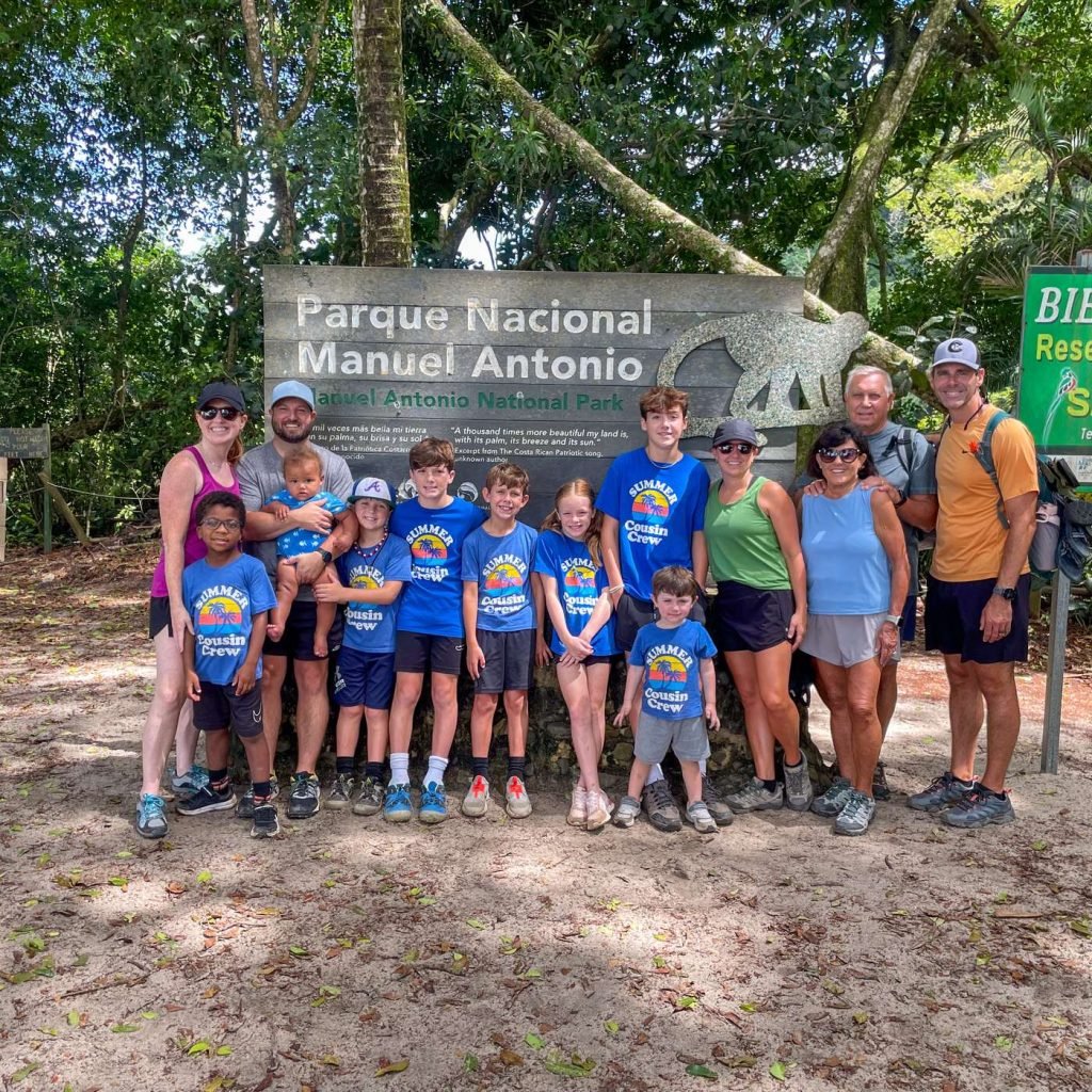 Family with young children at the Manuel Antonio National Park sign on a Wakoo Tours guided tour